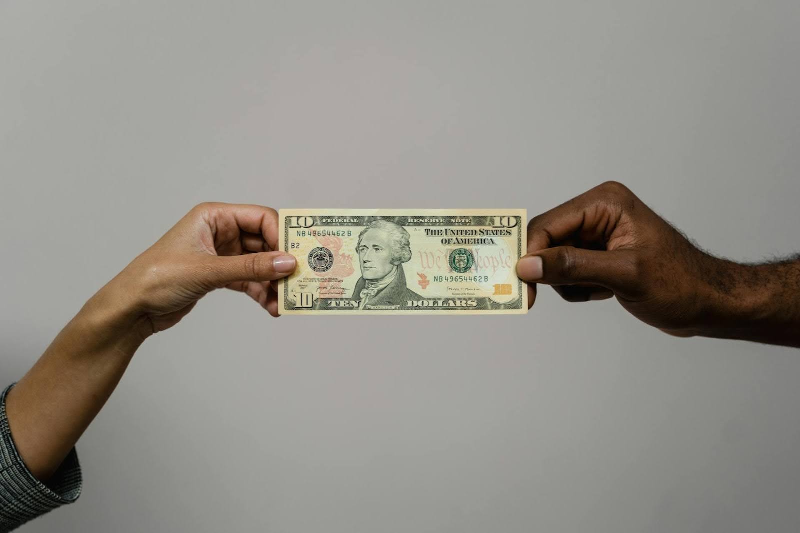 Two hands holding a $10 bill.