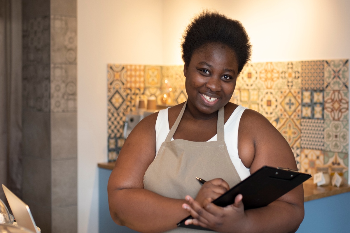 A coffee shop owner with papers and a laptop.