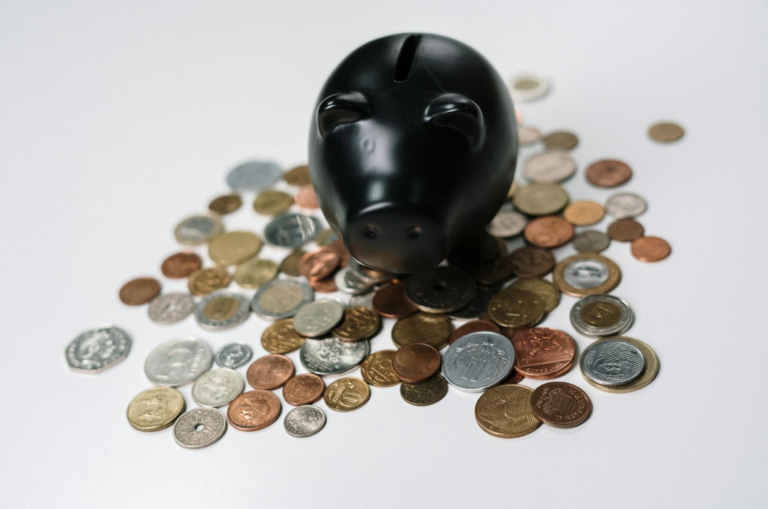 A black piggy bank in the middle of coins.