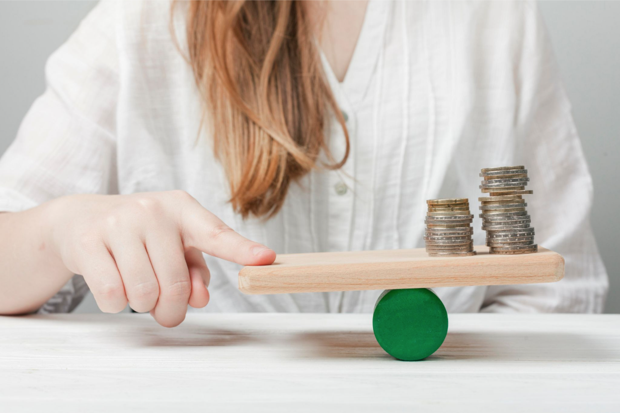 Woman balancing coins on a platform symbolizing financial instability.